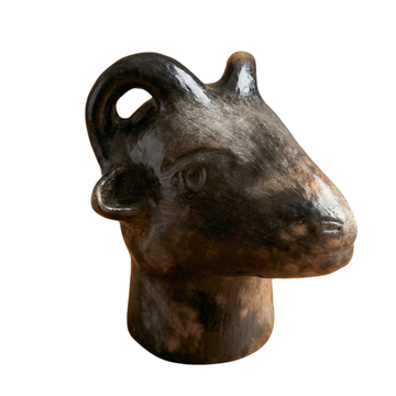 Estatua de terracota de una cabeza de carnero sobre fondo blanco.
